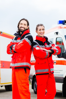 Rettungssanitäter*innen posieren vor ihrem Einsatzwagen